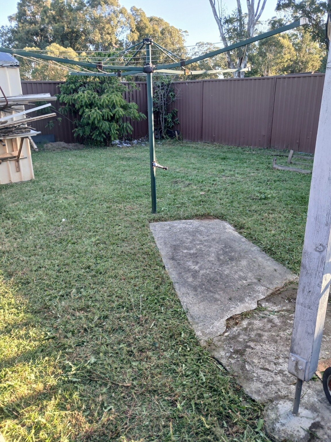 Tidy mowed backyard lawn around a rotary clothesline with a clean concrete pad